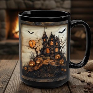 May include: A black ceramic mug featuring a wrap-around illustration of a haunted house on a hill with glowing orange pumpkins, bare trees, a full moon, and flying bats against a light-colored background framed by a dark wood-grain border.
