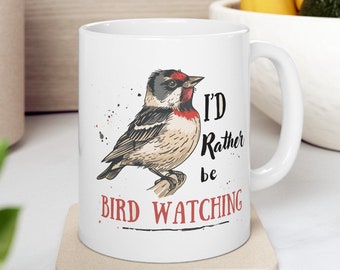 May include: White ceramic mug with a colorful illustration of a bird and the text "I'd Rather Be Bird Watching".