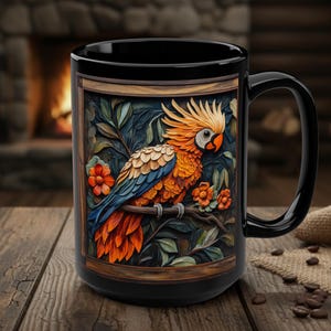 May include: Black ceramic mug featuring a detailed illustration of a colorful parrot perched on a branch, framed within a wooden border. The parrot has orange, yellow, and blue feathers, with red flowers and green leaves. The mug sits on a wooden table.