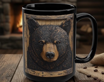 May include: Black ceramic mug featuring a detailed relief of a bear's face within a wooden frame. The bear has brown fur and a focused expression. The mug has a large handle and is set on a wooden surface, suggesting a rustic theme.