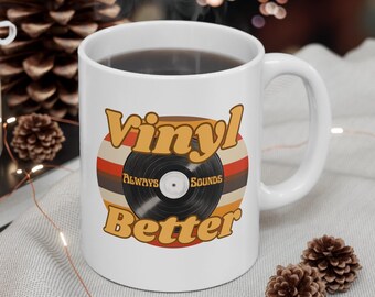 May include: White ceramic mug with a retro-style design featuring a black vinyl record with the text "Vinyl Always Sounds Better" in orange and brown lettering.