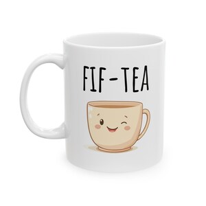May include: White ceramic mug with a black and white illustration of a smiling teacup with the text "FIF-TEA" printed on the front.