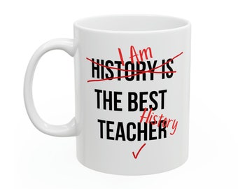 May include: White ceramic mug with black text that reads "I am History is the best History Teacher" with a red checkmark. The words "History is" are crossed out in red.