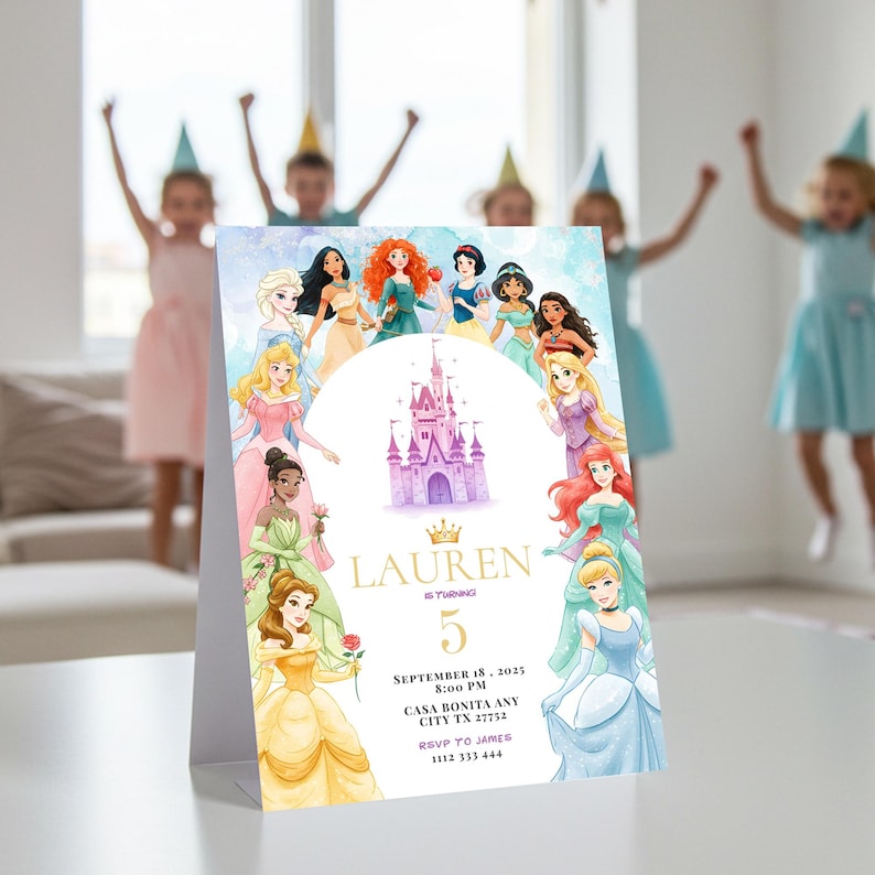 May include: A folded invitation card featuring illustrations of Disney princesses surrounding a castle. The card has the name "LAUREN" and the number "5" in gold lettering. The date, time, and location of the event are also printed on the card.
