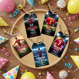 May include: A collection of five gift tags with soccer-themed designs. Each tag features a soccer player or jersey with the number 7 and the words "THANK YOU." The tags are on a wooden tray, surrounded by party decorations.