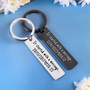May include: Two silver keyrings with black engraved tags. The tags read "It started with a message... 12/4/2023 14:12" and "It started with a message... 20/11/2017 20:25".