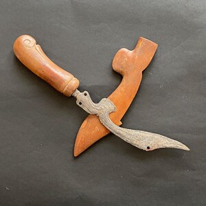 Peut inclure: Un couteau à manche en bois avec une lame courbe et un fourreau en bois. La lame est en métal et présente un motif de lignes. Le manche est brun et présente un motif sculpté. Le fourreau est brun et présente un design simple.