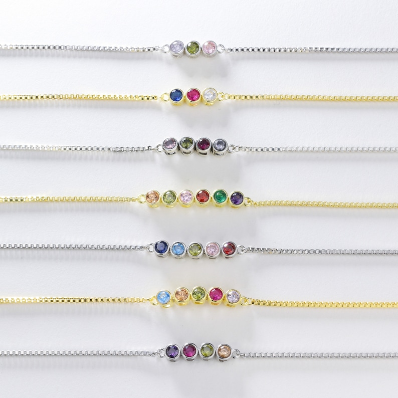 Puede incluir: Siete delicados brazaletes de cadena de oro con acentos de piedras preciosas de colores. Cada brazalete presenta una fila de cinco peque&ntilde;as piedras preciosas de diferentes colores, incluidos el azul, el verde, el rojo, el rosa y el morado.