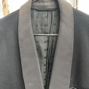 May include: A black tuxedo jacket with a satin lapel. The jacket is hanging on a hanger.