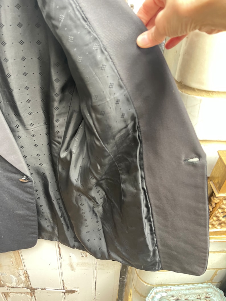 May include: Black blazer with a patterned lining. The blazer has a single button closure and a pocket on the left side.