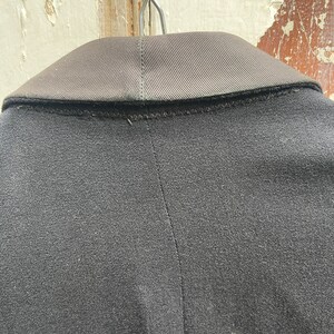 May include: Black blazer with a satin collar. The blazer is hanging on a hanger.