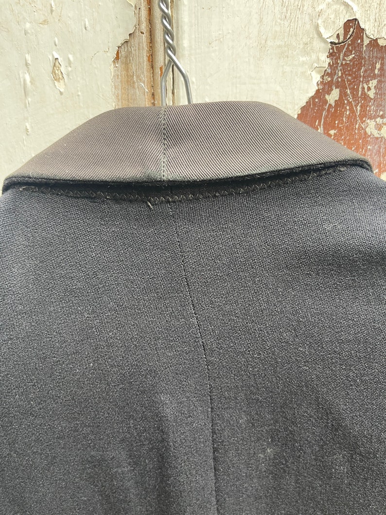 May include: Black blazer with a satin collar. The blazer is hanging on a hanger.