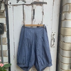 May include: A pair of blue cotton shorts with a gathered elastic waistband and a loose, wide-leg fit.