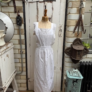 Antique white cotton pinafore apron with lace trim at shoulders