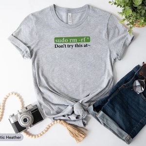 May include: Grey t-shirt with a green box that says "sudo rm -rf*" and the text "Don't try this at~" in black.
