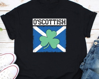 May include: Black t-shirt with the text "O'Scottish" above a design featuring a blue and white Scottish flag with a green shamrock in the center. The shirt is paired with white sneakers and blue jeans.