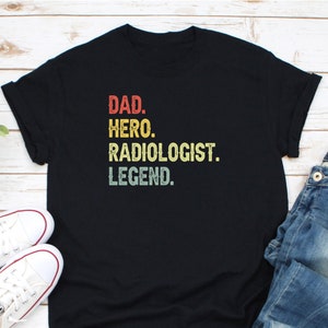 May include: Black t-shirt with a vintage-style graphic that reads "DAD. HERO. RADIOLOGIST. LEGEND."