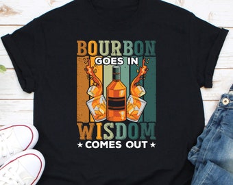 May include: Black t-shirt with a vintage-style graphic design featuring a bottle of bourbon and the text "Bourbon Goes In Wisdom Comes Out".
