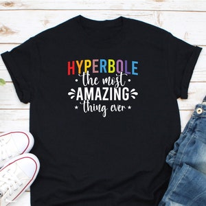 May include: Black t-shirt with white text that reads "HYPERBOLE - the most AMAZING thing ever" in rainbow colors.