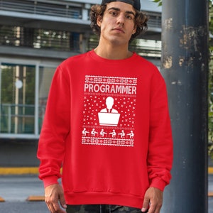 May include: Red Christmas jumper with a white snowflake pattern and the text "PROGRAMMER" in white. The jumper features a white silhouette of a person sitting at a computer.