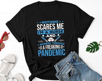 May include: Black t-shirt with a white graphic that says "Nothing scares me I'm a nurse and I worked through a freaking pandemic". The graphic also includes a red cross, a stethoscope, and a syringe.