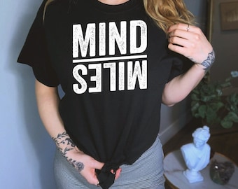 May include: Black t-shirt with white text that reads "MIND OVER MILES" in a distressed font.