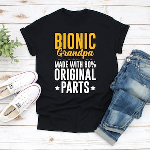 May include: Black t-shirt with the text "Bionic Grandpa Made with 90% Original Parts" in yellow and white lettering.
