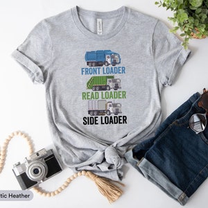 May include: A gray t-shirt with a graphic of three garbage trucks and the text "Front Loader", "Read Loader", and "Side Loader".