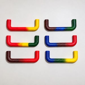 May include: Six U-shaped cabinet handles arranged in two columns. Each handle features a textured surface with a gradient color transition. The colors include combinations of red, yellow, green, blue, and brown, applied in distinct color-blocked segments.