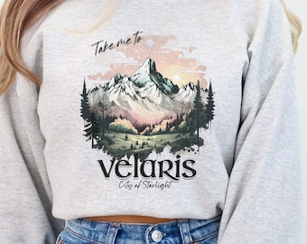 Puede incluir: Una sudadera gris recortada con un estampado gráfico de una cordillera y el texto "Take me to Velaris City of Starlight".