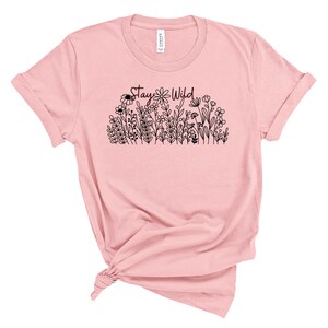 May include: A pink t-shirt with a black graphic of flowers and the text "Stay Wild".