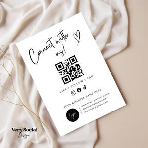 Op de afbeelding: Zwart-witte QR-code met de tekst "Connect with us!" en een hartje. Onder de QR-code staat de tekst "Like | Follow | Tag" met pictogrammen voor Instagram, Facebook en TikTok. De tekst "Your Business Name Here" staat onder de pictogrammen, gevolgd door een websiteadres, een social media-handle en een e-mailadres. De tekst "Logo" staat in een cirkel onder de bedrijfsnaam.