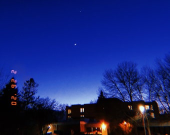 以下が含まれることがあります： 暗い青色の夜空に三日月と星が輝き、手前に建物のシルエットと木々が見える