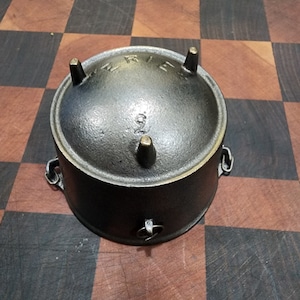 May include: A black cast iron pot with three legs and a handle. The pot has the word "WREID" embossed on the side.