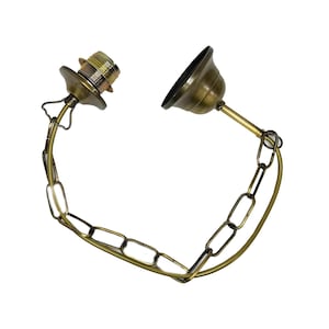 Könnte beinhalten: Eine goldfarbene Metallkette mit einem dekorativen Metalldeckel an jedem Ende. Die Kette dient zum Aufhängen einer Leuchte.