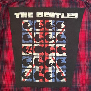 May include: A black patch with the text "THE BEATLES" in white letters. The patch features a grid of 16 squares, each containing a black and white silhouette of a face with a Union Jack flag background.