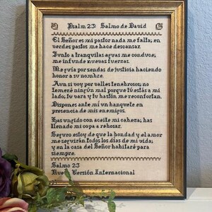 May include: A framed print of Psalm 23 in Spanish, with the title "Salmo de David" and the text "El Señor es mi pastor nada me falta, en verdes pastos me hace descansar..." The print is on a beige background with brown and gold accents.