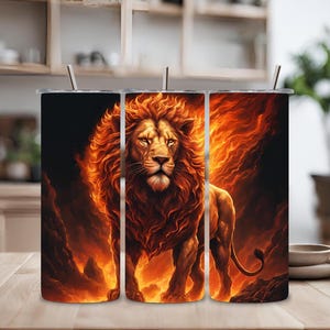 Puede incluir: Tres vasos de acero inoxidable con un diseño de un león con llamas detrás. El león es naranja y amarillo con una melena negra. El fondo es negro con llamas naranjas y amarillas.