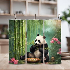Puede incluir: Un juego de tres vasos de acero inoxidable con un oso panda comiendo bambú en un bosque de bambú. Los vasos tienen un diseño verde, blanco y negro.