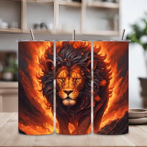 Puede incluir: Tres vasos de acero inoxidable con un diseño de cara de león rodeado de llamas y flores. El león tiene una melena negra y una expresión feroz.