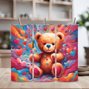 Puede incluir: Tres vasos de acero inoxidable con un diseño colorido que presenta un osito de peluche rodeado de corazones. El fondo es un remolino de rosa, azul, naranja y amarillo.