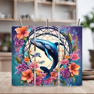 Puede incluir: Tres vasos de acero inoxidable con un diseño floral colorido y una ballena azul saltando a través de un atrapasueños. El atrapasueños está hecho de cuerda marrón y cuentas.