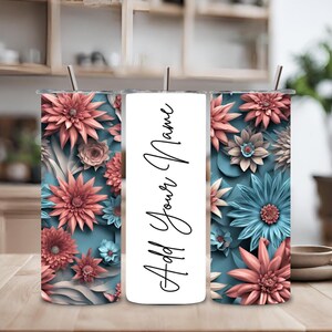 Puede incluir: Tres vasos de acero inoxidable con un diseño floral. Los vasos presentan un patrón floral azul y rosa con el texto "Add Your Name" en el vaso del medio.