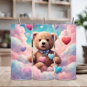 Puede incluir: Tres vasos de acero inoxidable con un diseño de un osito de peluche que sostiene corazones en un cielo con nubes. El osito de peluche es marrón y los corazones son rosas, azules y rojos.