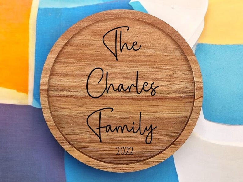 May include: A round wooden coaster with the text "The Charles Family 2022" engraved in black.