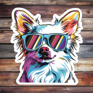 Könnte beinhalten: Eine farbenfrohe Illustration eines Chihuahuas, der eine blaue Sonnenbrille mit einem Regenbogenmuster auf den Gläsern trägt. Das Fell des Hundes ist in Blautönen, Lila, Rosa und Gelb bemalt.