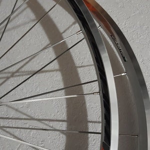 May include: A silver bicycle wheel with a black rim and red accents. The wheel has a Mavic logo on the rim.