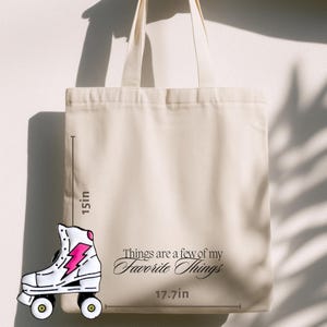 May include: Cream-colored tote bag with the text "Things are a few of my Favorite Things." A roller skate graphic with a pink lightning bolt is on the left. The bag is 15 inches tall and 17.7 inches wide.