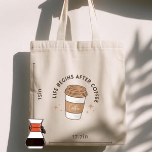 Puede incluir: Un bolso tote beige, de 38 cm de alto y 45 cm de ancho, con la frase "LIFE BEGINS AFTER COFFEE" alrededor de un gráfico de taza de café. Un pin de cafetera se muestra en la parte inferior izquierda.