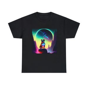 May include: Black t-shirt featuring a colorful graphic of a dog sitting on a rock with a vibrant, otherworldly background. The design includes a large, glowing planet and stylized mountains, creating a fantasy scene.